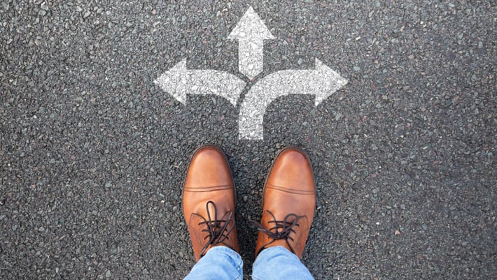 Eine Person steht vor Pfeilen, die in verschiedene Richtungen zeigen. Symbolbild für die Entscheidung für das richtige Marketing Automation Tool.